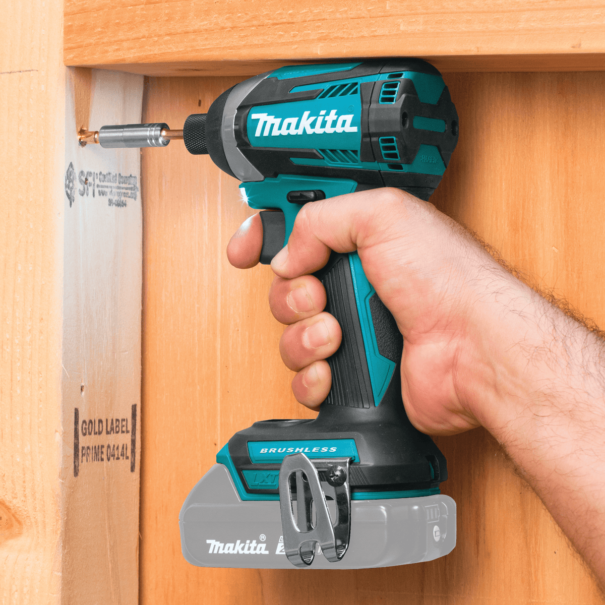 Compact 4-5/8-inch Makita impact driver fits between narrow 2x4 wood wall studs to drive fasteners in tight corners.