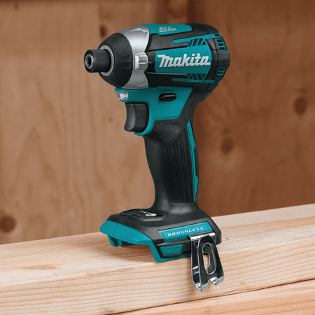 Makita XDT14Z 18V LXT cordless brushless impact driver resting upright on a 2x4 lumber framing board in a workshop.