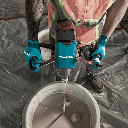 Overhead action shot of a contractor using the Makita 40V XGT cordless mixer to mix wet material in a large tub.