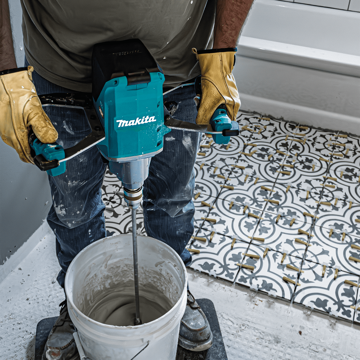 Contractor using the Makita 40V XGT cordless mixer over a tile installation bucket on a bathroom remodeling project.