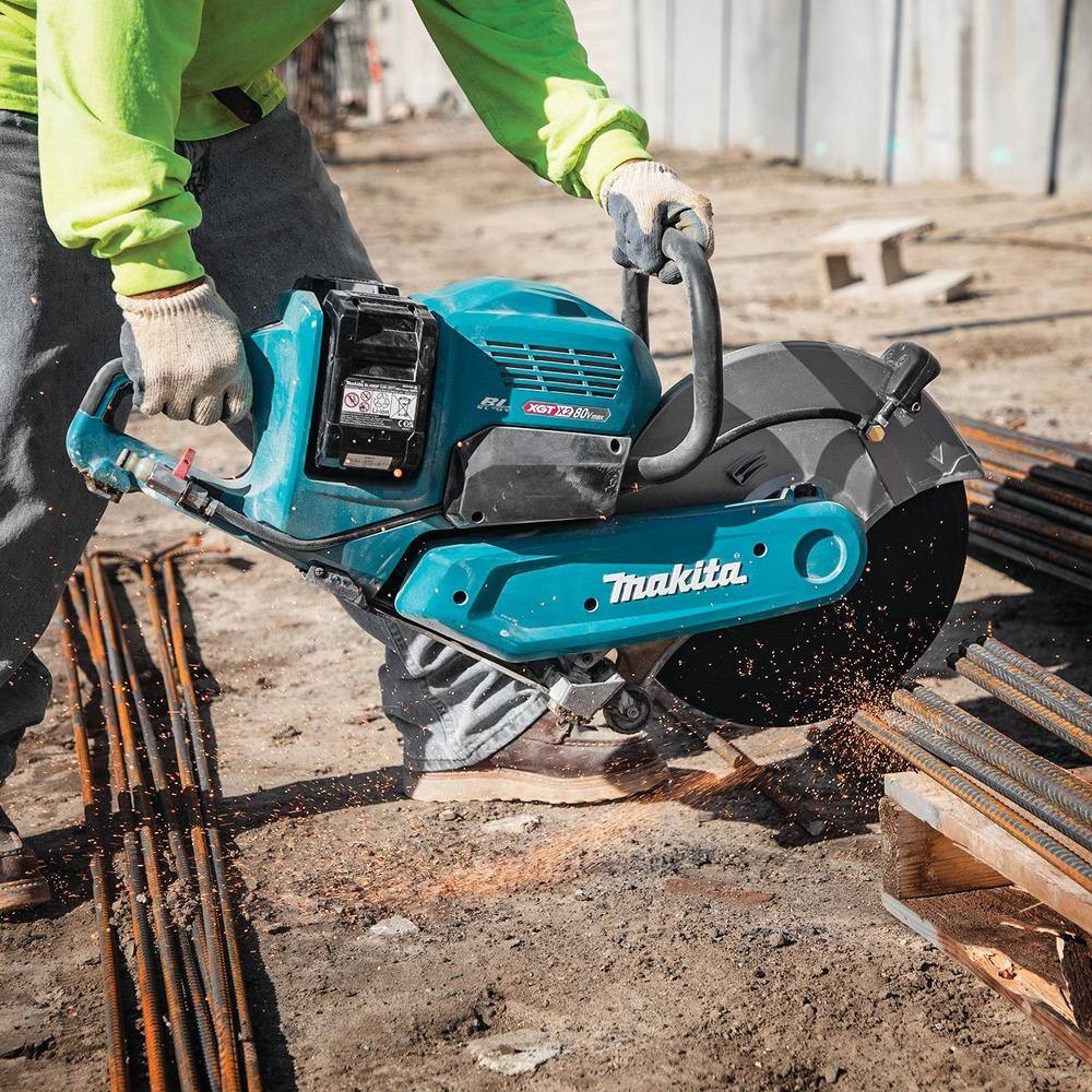 A construction worker cutting down through an array of loose steel rebar reinforcement rods laid over wood blocking on a jobsite using the Makita 80V Max XGT brushless power cutter.