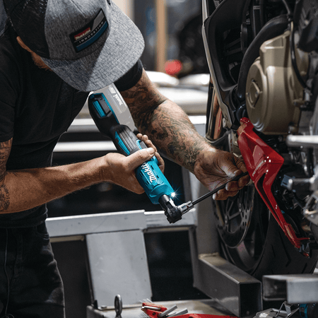 Motorcycle mechanic using the Makita XRW01Z 18V cordless ratchet with an extended bit socket to service fairing bolts in tight engine bays.