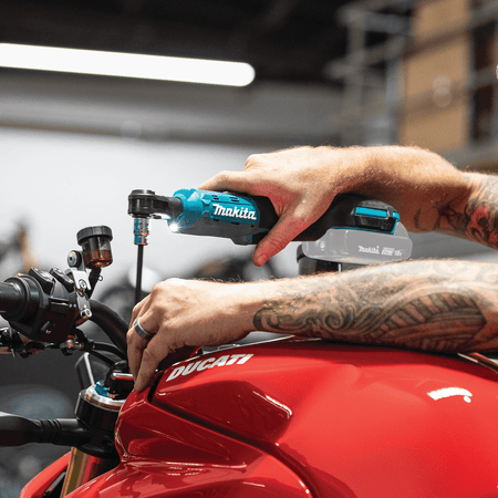 Technician using the low-profile head and LED light of the Makita XRW01Z ratchet to fasten handlebar hardware without scratching painted panels.