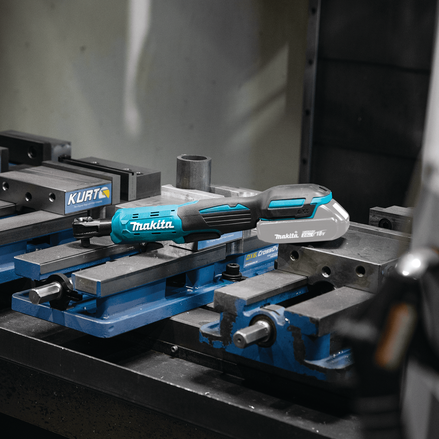 Makita XRW01Z 18V LXT cordless drive ratchet resting on a machinist's workbench vise for quick access during mechanical assembly.