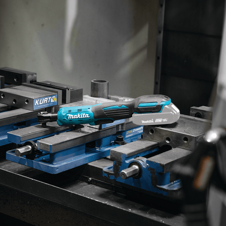 Makita XRW01Z 18V LXT cordless drive ratchet resting on a machinist's workbench vise for quick access during mechanical assembly.
