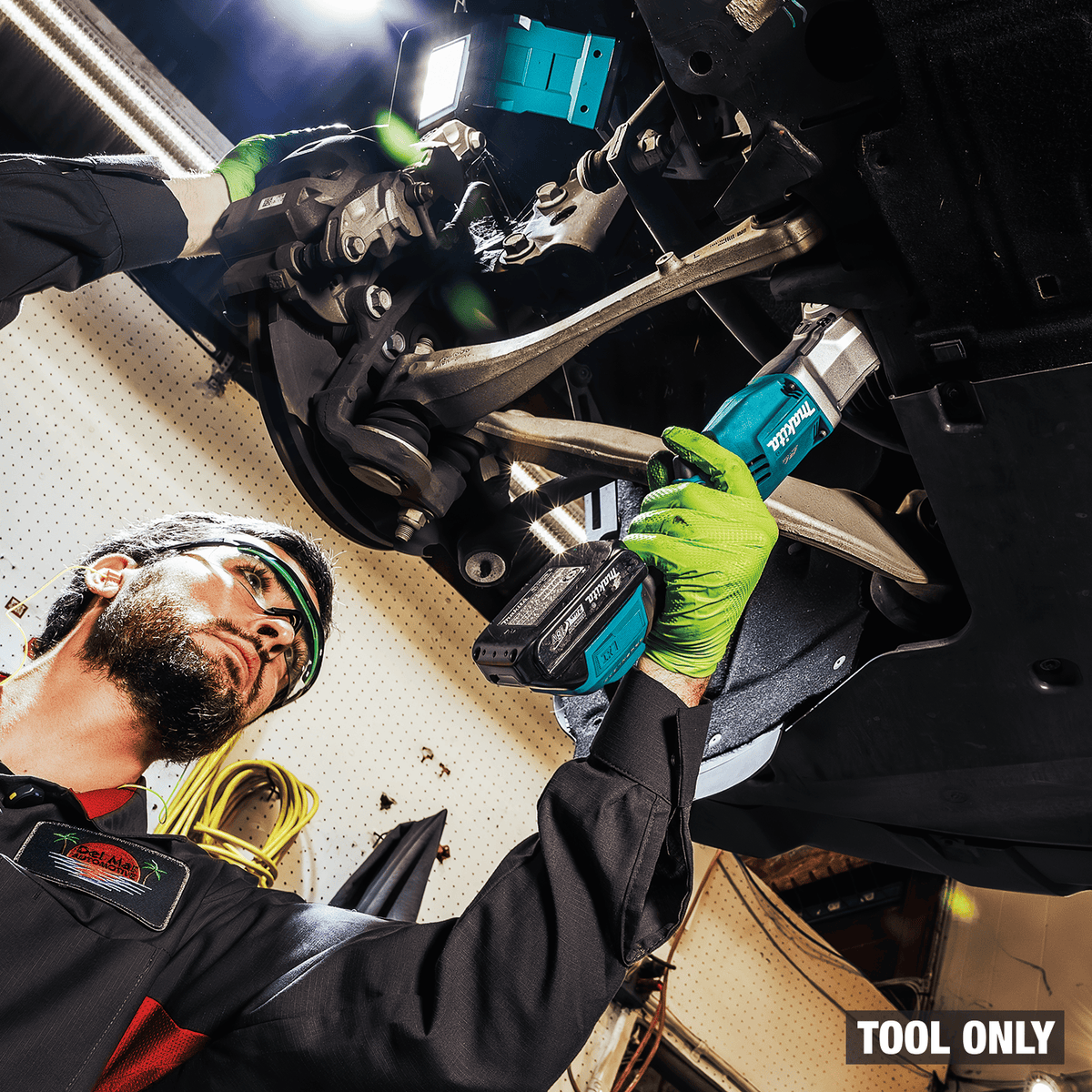 Technician loosening steering knuckle bolts with the compact Makita XLT05Z angle impact wrench in a tight wheel well.