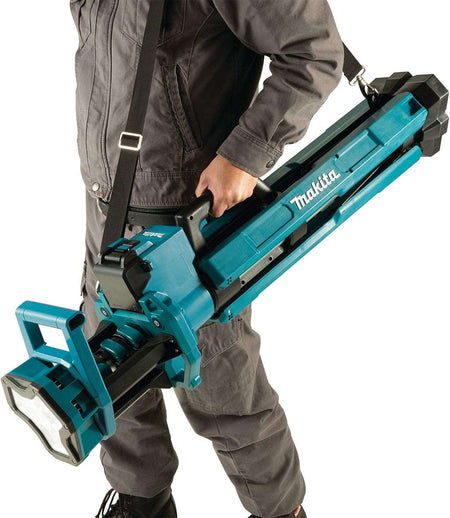 A tradesperson transporting the folded Makita DML813 tower work light using the included padded shoulder strap for convenient hands-free mobility across a site.