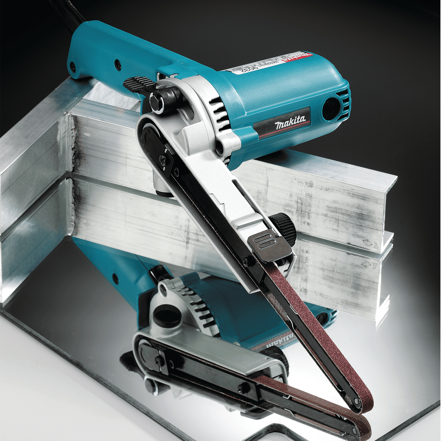 Makita 9032 belt sander with its arm pivoted to clean and blend internal corner weld joints on structural aluminum channel stock.