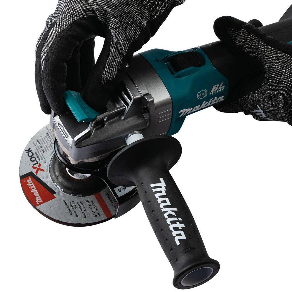 Action shot of a worker in protective gear pulling the X-LOCK release lever to demonstrate the rapid, tool-free removal of a 5-inch wheel from the Makita XGT angle grinder.