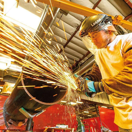 A metal fabricator utilizing the Makita GAG11Z brushless grinder on a heavy-duty steel workpiece, showcasing the intense spark production and efficiency of the 40V Max XGT system.