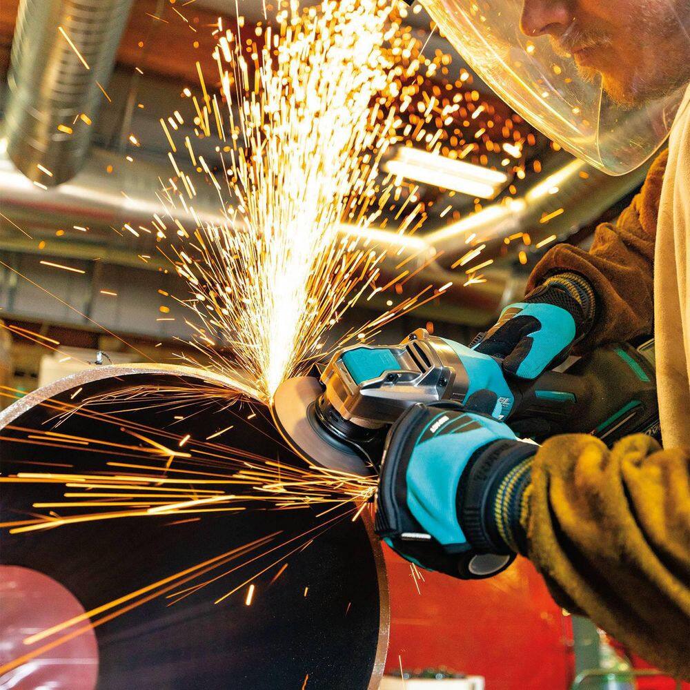 Professional fabricator using the Makita X-LOCK angle grinder to smooth a heavy metal edge, highlighting the cordless power and high-speed spark production during industrial metalwork.