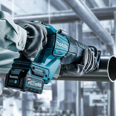 A professional in protective gear using the Makita GRJ01M1 brushless reciprocating saw to perform a heavy-duty cut on a large diameter metal pipe in an industrial construction environment.