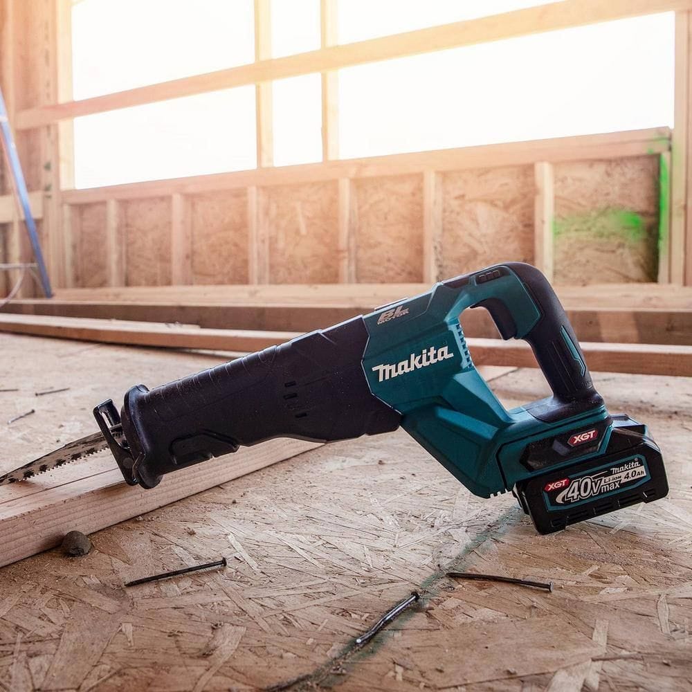 A lifestyle shot of the Makita 40V Max XGT reciprocating saw resting on a wooden subfloor at a construction site, surrounded by nails to show its rugged build quality and portability.
