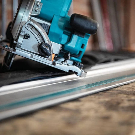 Close-up detail view of the saw's magnesium base plate sitting perfectly on a guide rail track, highlighting the compatibility feature.