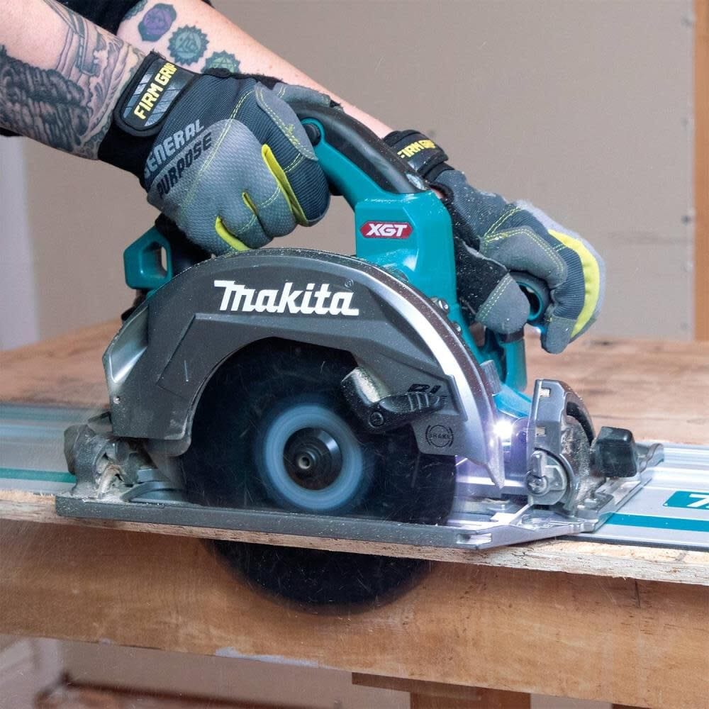 Action shot of a worker using the circular saw on a guide rail track to perform a long rip cut on a wooden panel.
