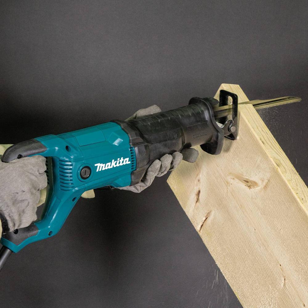 Action shot of a professional installer using the Makita JR3051T reciprocating saw to cut through thick wooden framing, demonstrating the tool's power and 3,000 SPM performance.