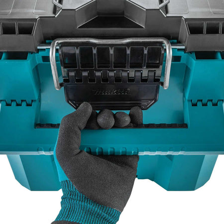 A close-up shot of a tradesperson in a safety glove using the robust comfort-grip carrying handle on the Makita T-90021 tool box, emphasizing ease of transportation for heavy loads.