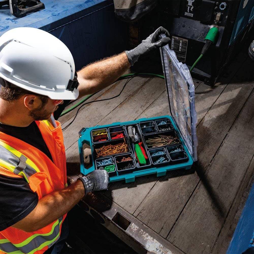 A construction professional in a hard hat and safety vest using the Makita MAKTRAK T-90059 organizer on a jobsite, emphasizing the tool's portability and efficient modular organization.