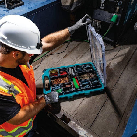 A construction professional in a hard hat and safety vest using the Makita MAKTRAK T-90059 organizer on a jobsite, emphasizing the tool's portability and efficient modular organization.