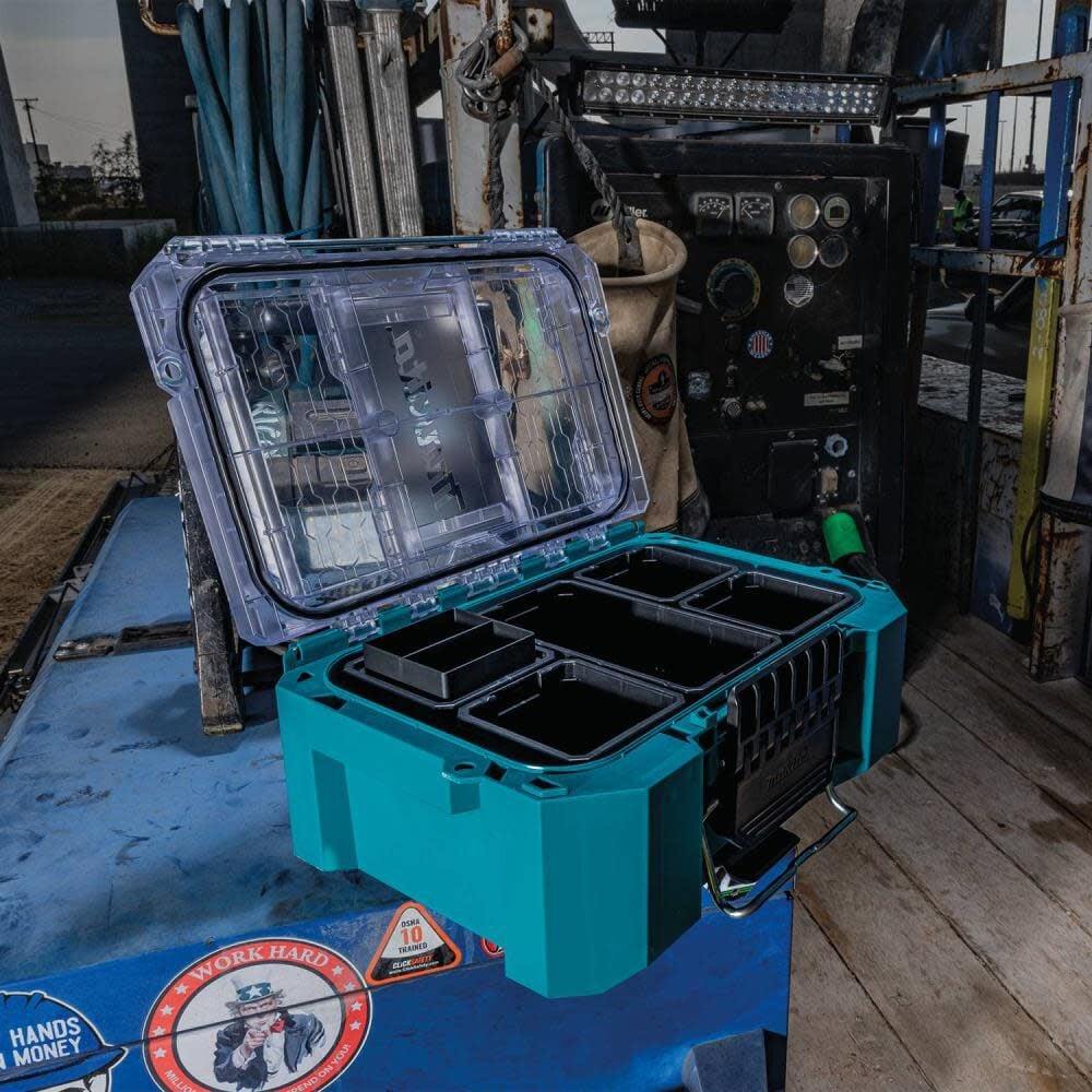 Angled jobsite shot of the open Makita T-90065 modular organizer, highlighting the 5-inch deep black storage bins and the impact-resistant clear lid in a real-world work environment.