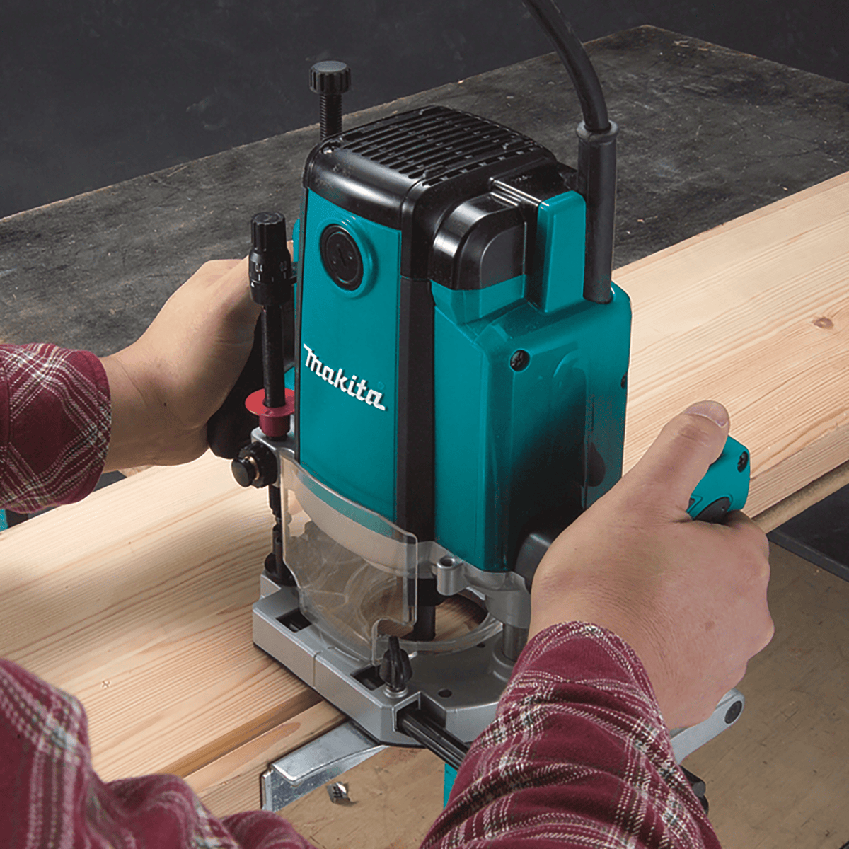 Craftsman using Makita RP1800 plunge router with parallel fence to mill straight dado grooves into lumber stock.