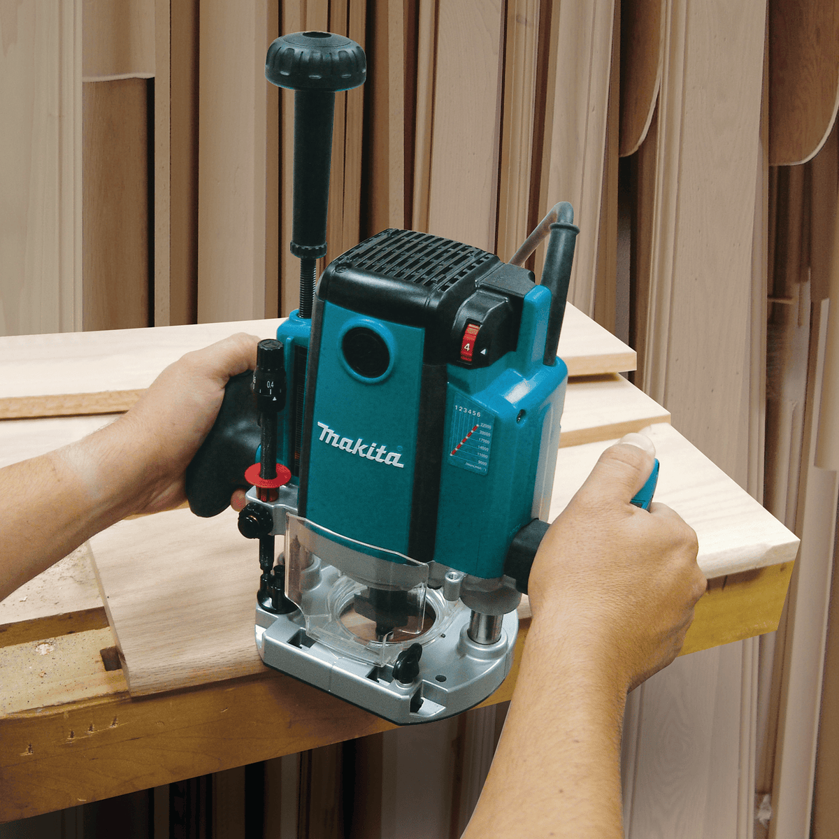 Woodworker guiding the Makita RP2301FC 3-1/4 HP plunge router with extended depth knob across hardwood edge profile.