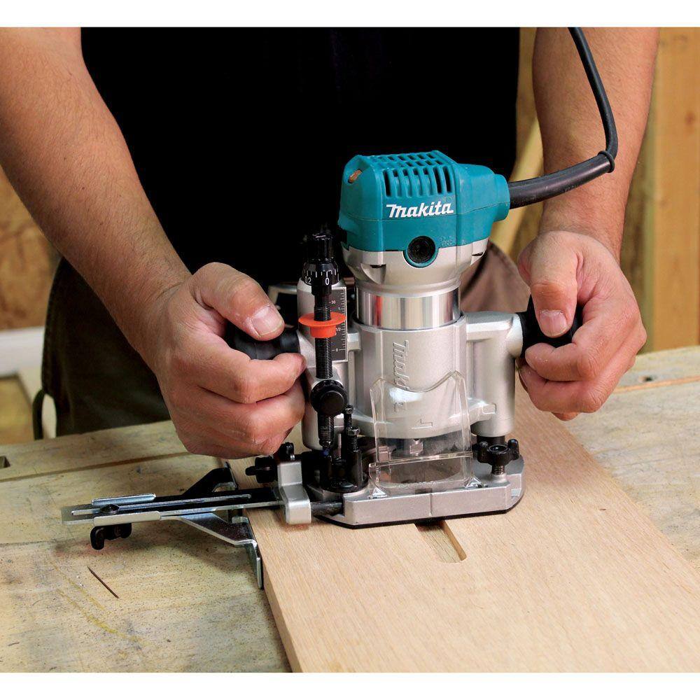 Action shot of a woodworker using the Makita RT0701CX7 plunge base router with a straight guide attachment to make a precise groove in a wooden board.