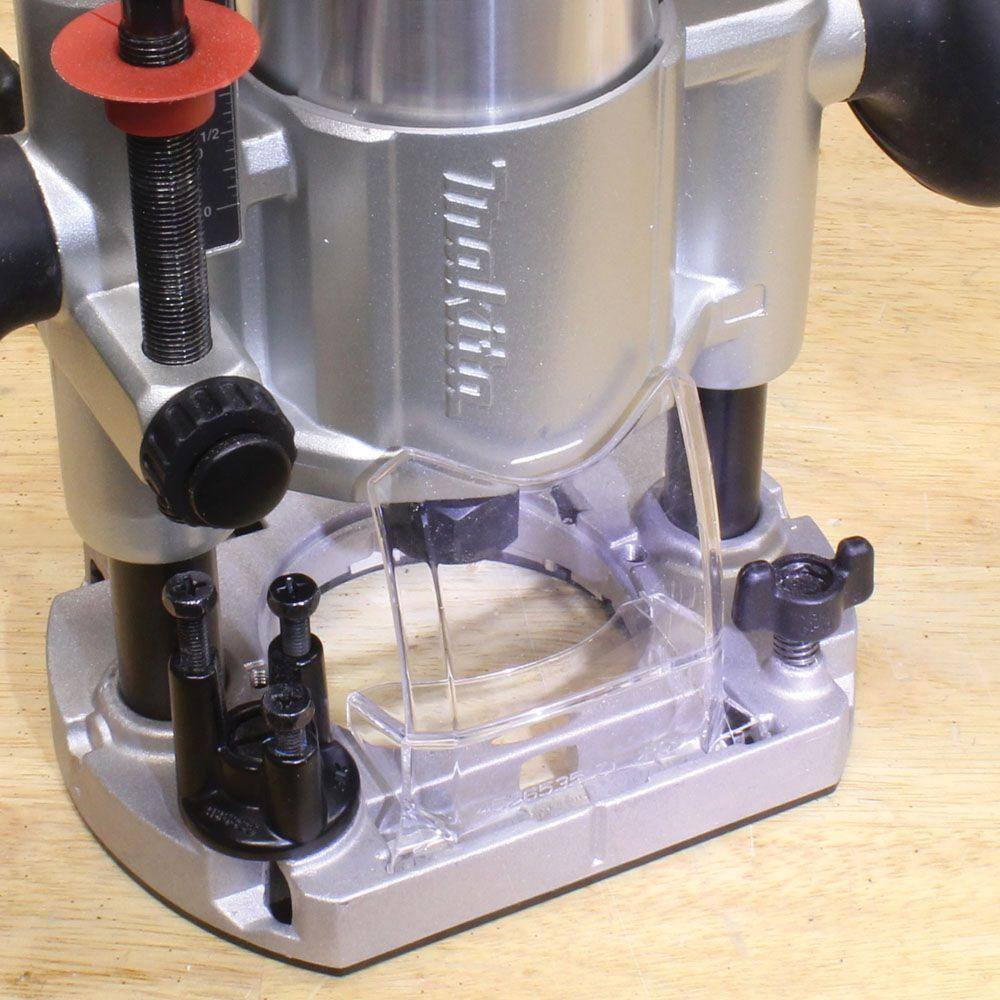 Close-up of the Makita RT0701CX7 compact router installed in the plunge base, highlighting the removable clear plastic shield for debris deflection.