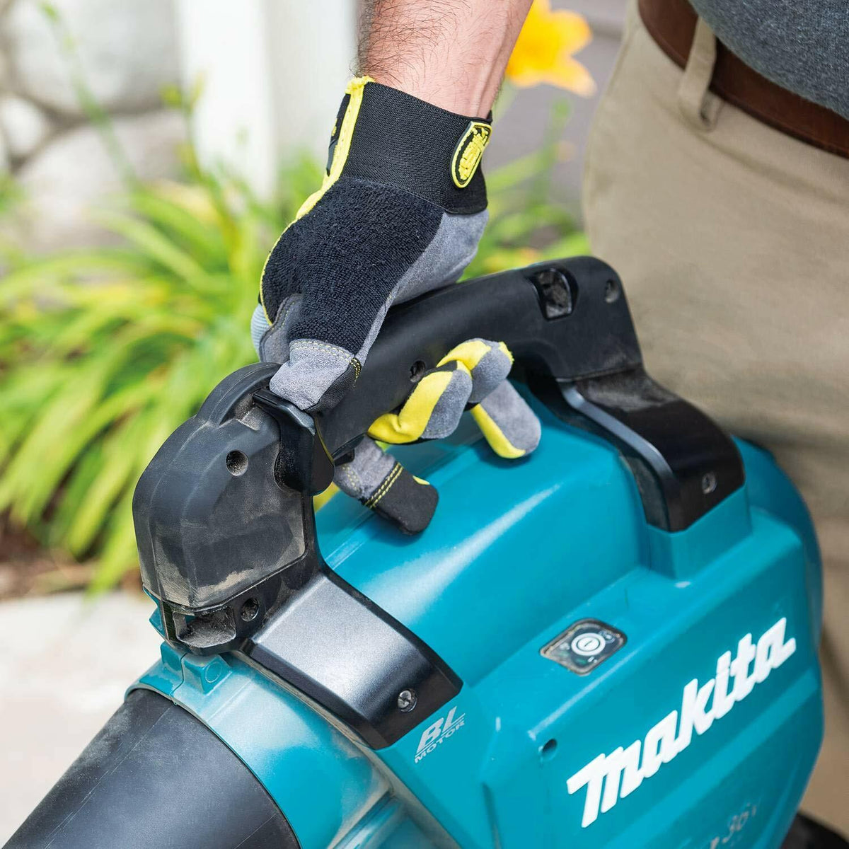 Close-up of a user's gloved hand gripping the carry handle of the Makita XBU04Z blower, emphasizing the rubberized soft grip and ergonomic design.
