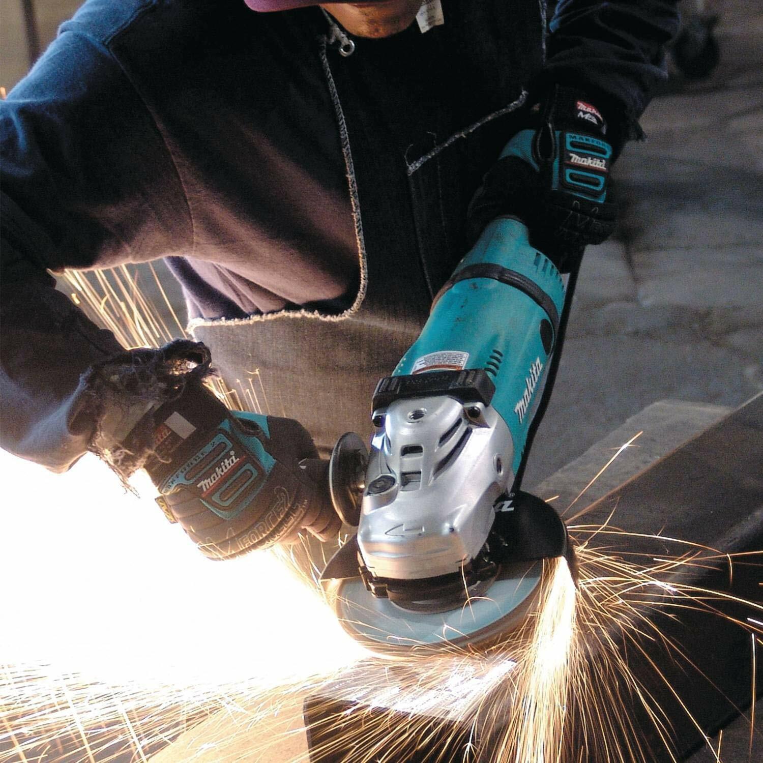 Action shot of a worker using the Makita 7-inch angle grinder to grind metal, producing a dense shower of bright orange and yellow sparks.