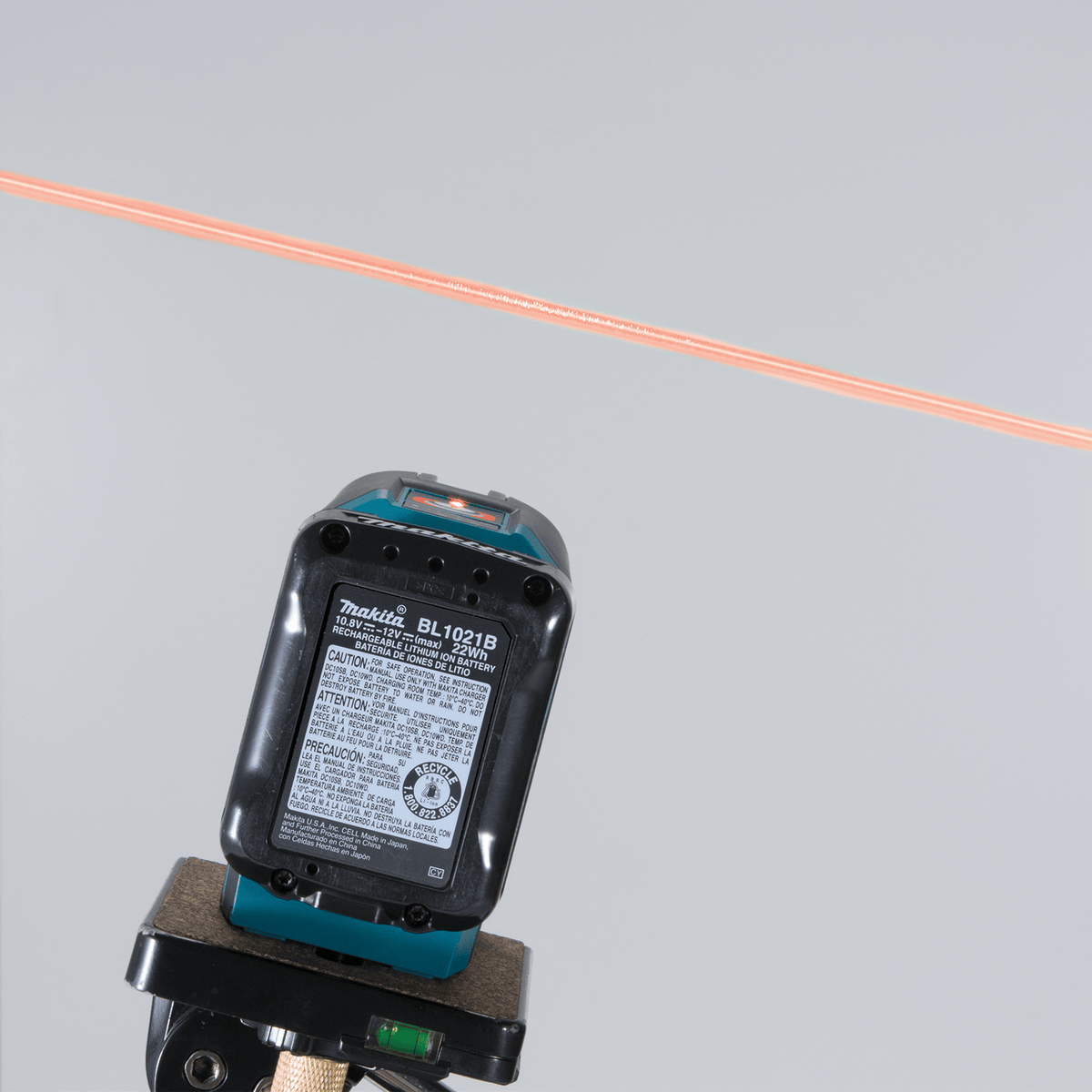 Tripod-mounted Makita SK105D 12V max CXT laser projecting a level red reference beam across a commercial interior wall.