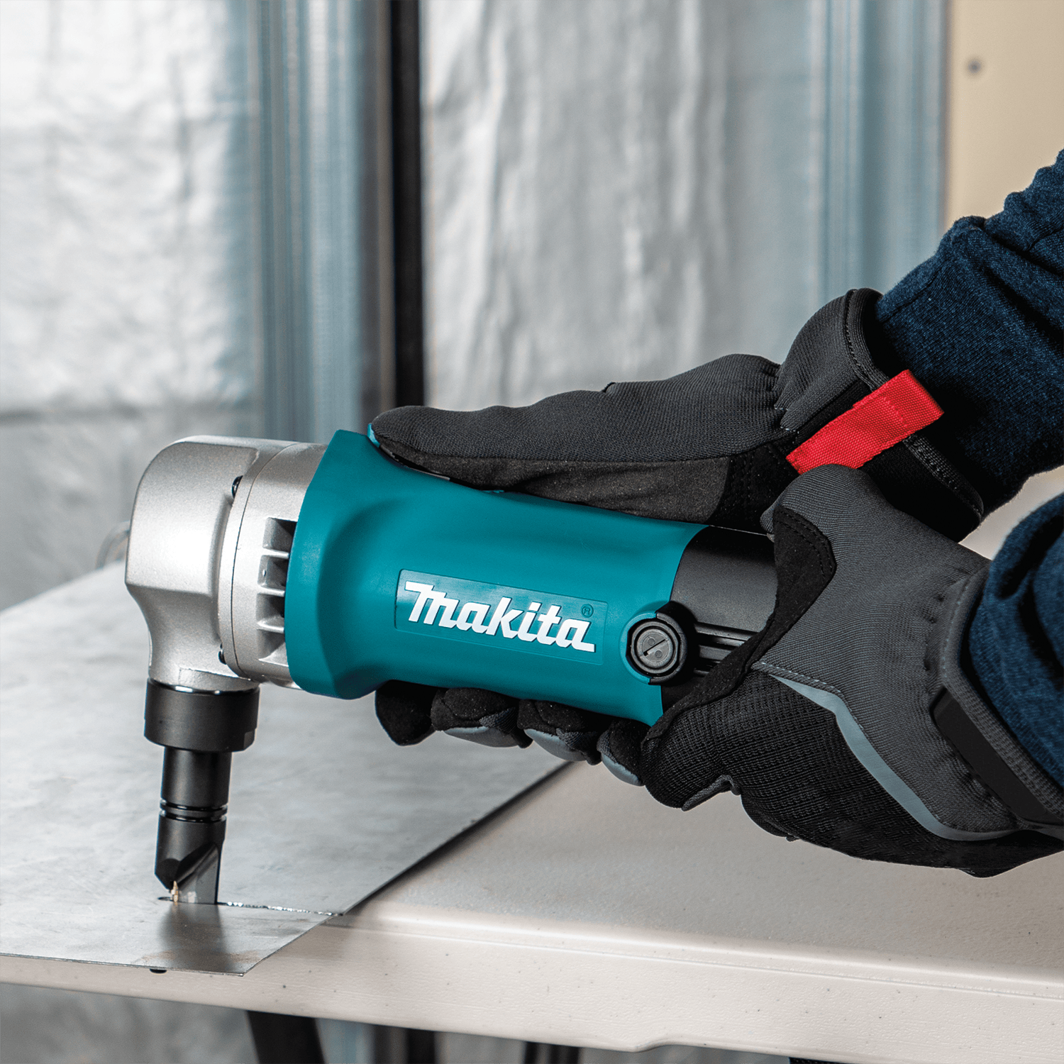 Operator cutting flat sheet metal with the Makita JN1601 nibbler to make clean, distortion-free straight shears.