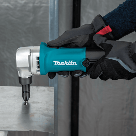 Technician making an internal cutout in a metal plate using the 1/4-inch punch stroke of the Makita JN1601 nibbler.