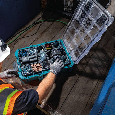 Action shot of a professional contractor in high-visibility gear accessing hardware from the Makita T-90043 organizer, demonstrating the 360-degree clear lid and stable modular base on a jobsite.