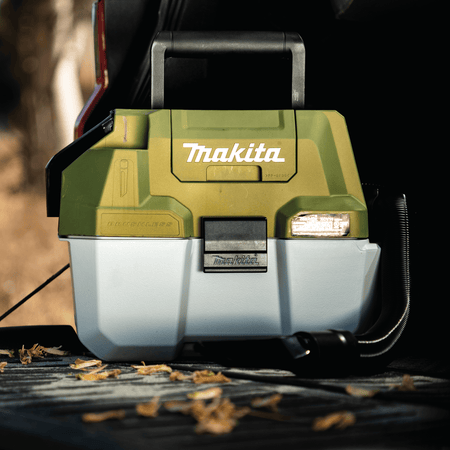Compact 2-gallon Makita ADCV11Z cordless vacuum resting on a truck bed for convenient mobile jobsite and campsite cleanup.