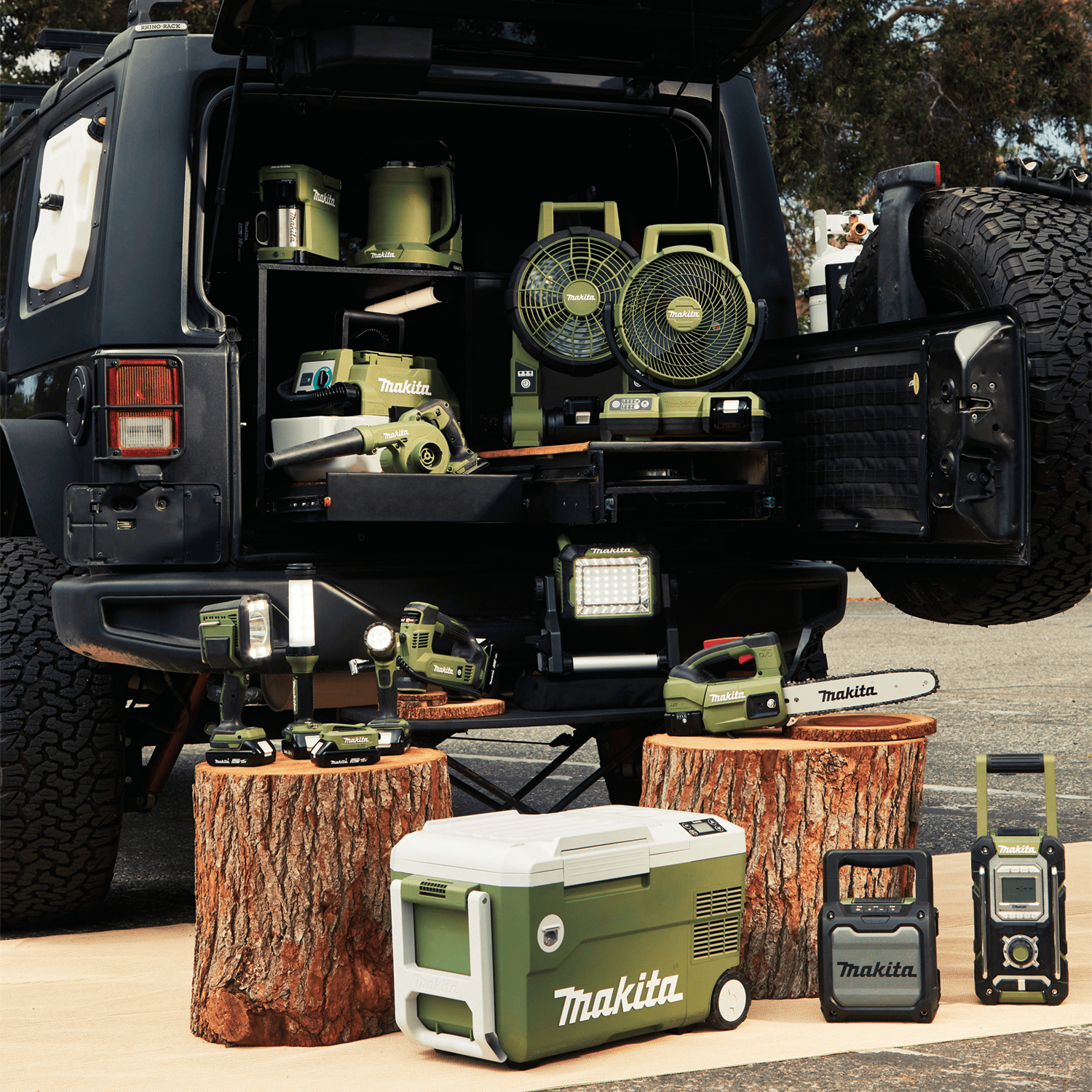 Makita Outdoor Adventure 18V LXT cordless tool ecosystem displayed in an off-road SUV tailgate setup including the ADML811 area light.