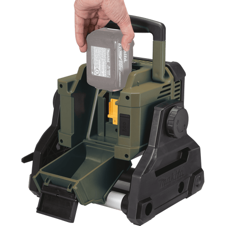 Hand inserting a 5.0Ah 18V LXT lithium-ion battery into the rear weather-sealed battery compartment of the Makita ADML811 area floodlight.