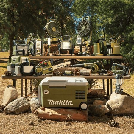 Comprehensive lineup of the Makita Outdoor Adventure 18V LXT cordless system displayed on a outdoor picnic table, featuring the ADRM13 lantern.