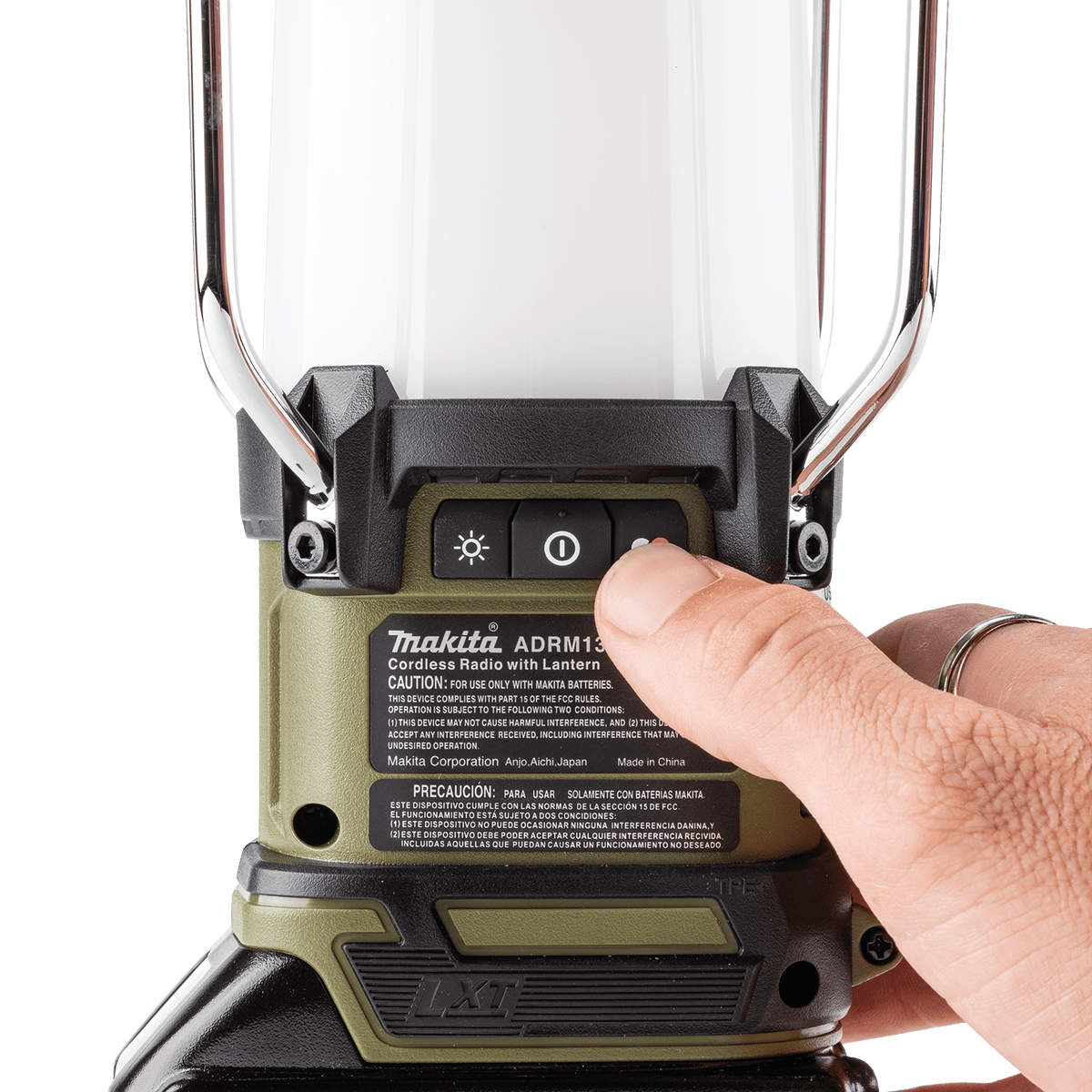 Finger pressing the top lighting control button on the Makita ADRM13 lantern to select light modes and color temperatures.