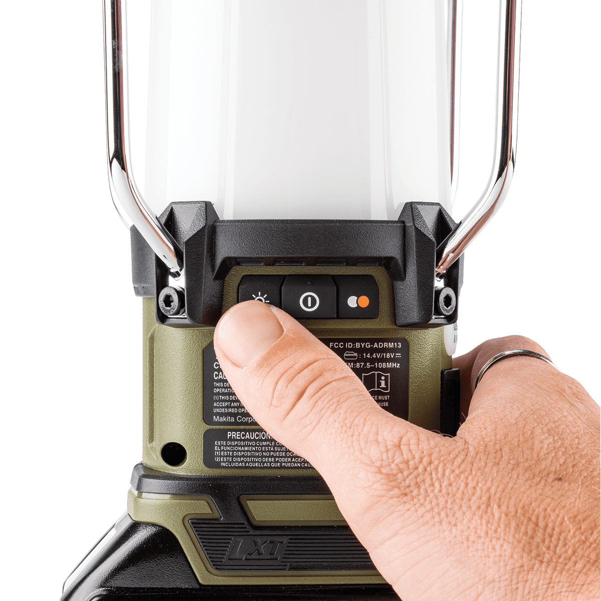 Gloved hand toggling the rear power button on the Makita ADRM13 18V LXT Bluetooth radio and LED lantern.
