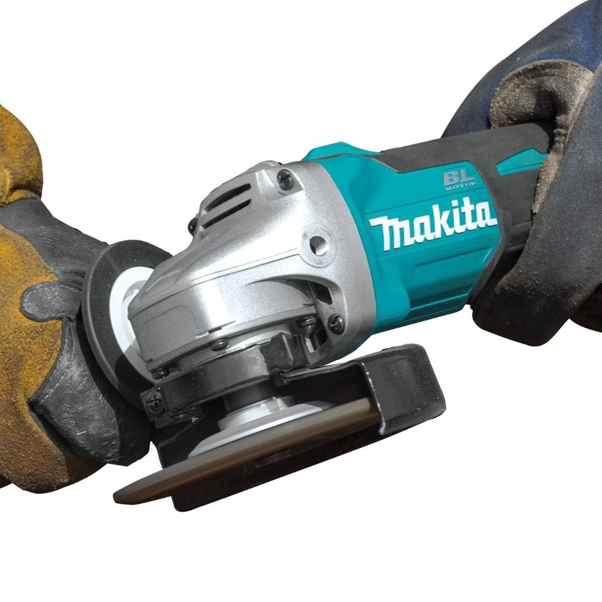 A worker wearing heavy gloves uses the Makita cordless grinder to grind the edge of a metal plate, creating sparks.