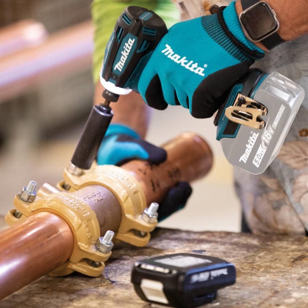 A professional plumber using the Makita XDT19Z impact driver with a socket attachment to secure a heavy-duty pipe clamp, demonstrating the tool's 1,590 in.lbs. of Max Torque.