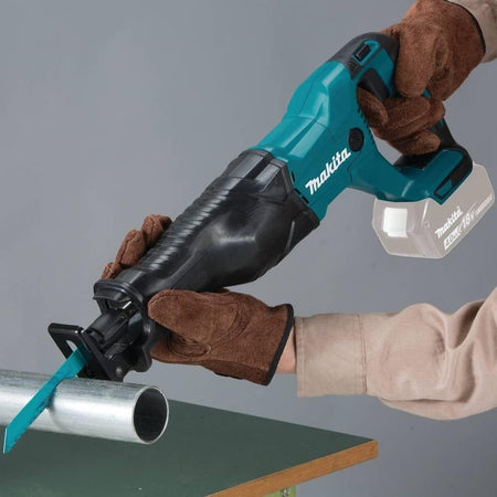 A worker wearing brown gloves uses the Makita reciprocating saw to cut through a metal pipe.