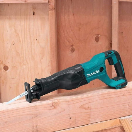 The Makita reciprocating saw resting on bare wooden wall framing at a construction site.