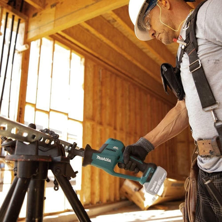 Action shot of a construction worker wearing safety glasses using the reciprocating saw to cut a metal pipe securing in a tripod vise.