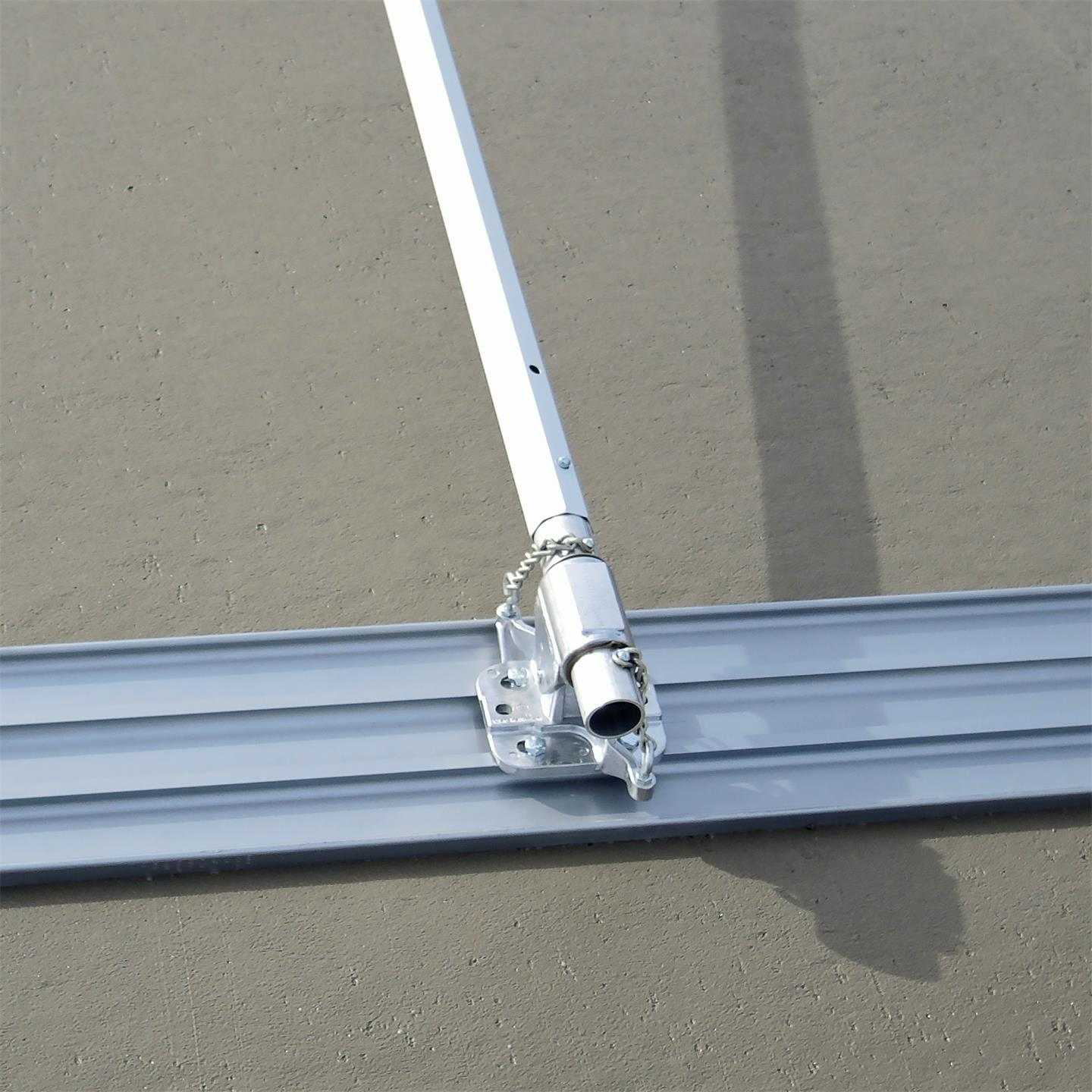 High angle view of the magnesium bull float blade attached to a handle bracket and pole resting on a finished concrete slab.