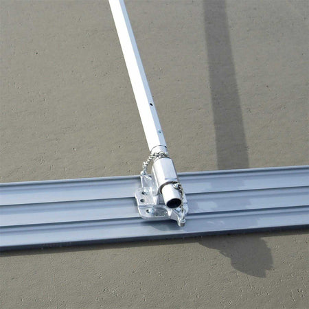 High angle view of the magnesium bull float blade attached to a handle bracket and pole resting on a finished concrete slab.