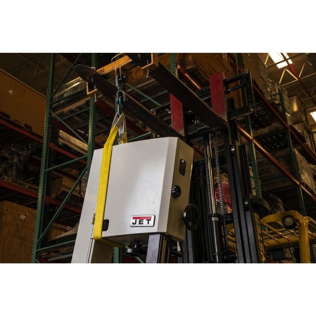 A yellow Jet web sling is shown in a vertical lift, attached to a forklift, safely lifting a large piece of Jet-branded machinery in a warehouse.