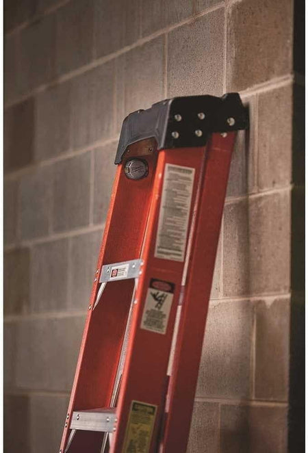 Jobsite photo showing the Milwaukee TICK tracker mounted to the top side rail of an orange fiberglass extension ladder.