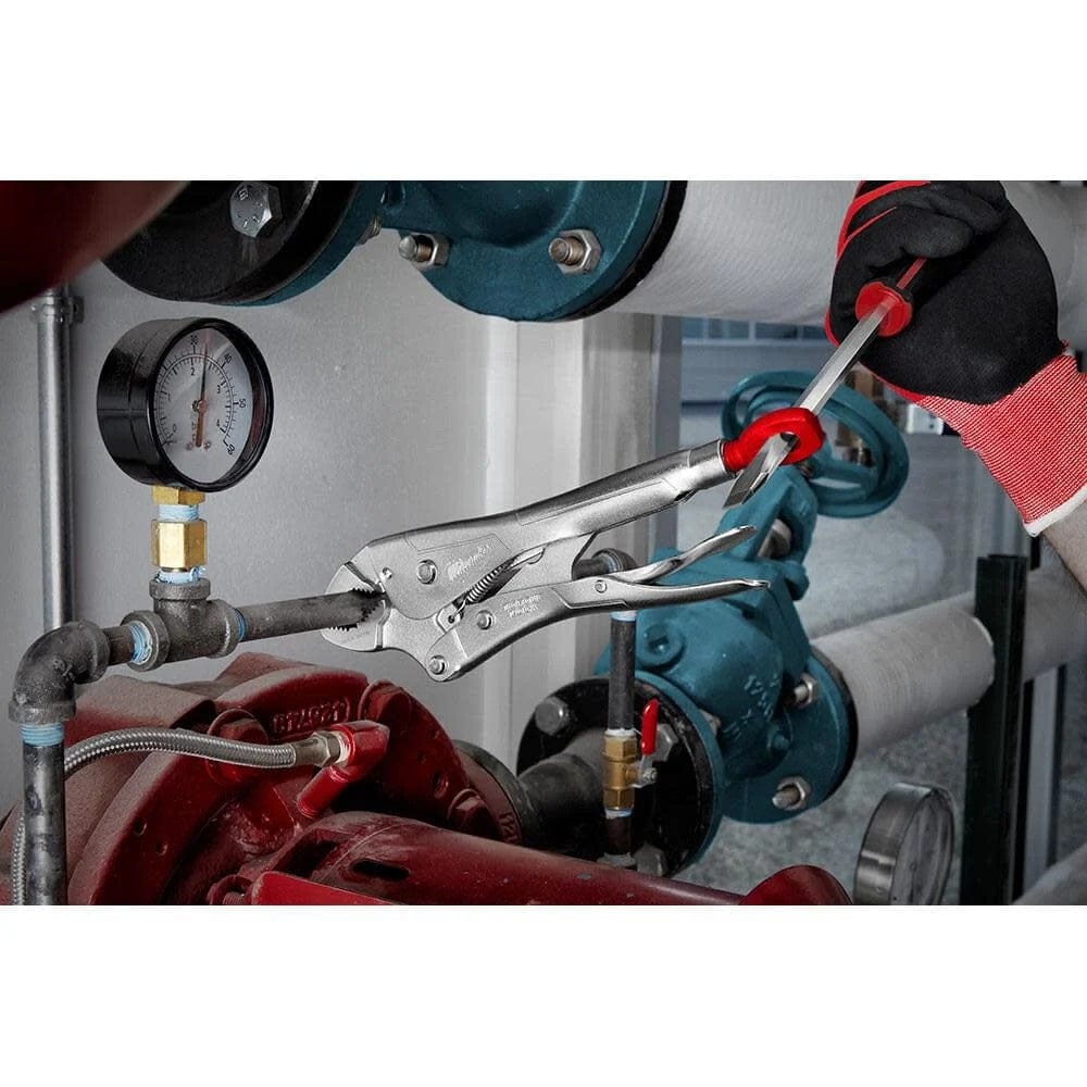 Close-up action shot of a hand using a screwdriver inserted through the Torque Lock loop to tighten the locking pliers onto a metal pipe in an industrial setting.